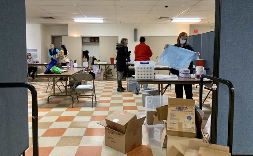 A small group of people unpack supplies inside a vaccine clinic in Nashua