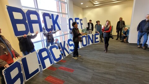 Roxanne Pacheco speaks to a group protesting the potential sale of PNM to Blackrock before the public hearing at the University of New Mexico