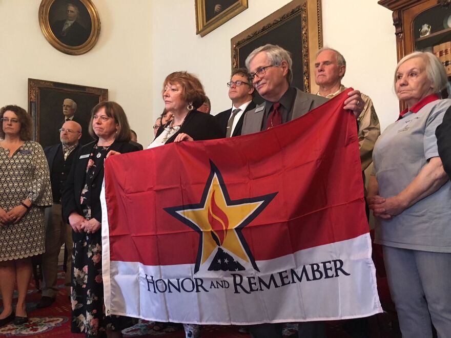 Lawmakers hold up the "Honor and Remember" flag during a bill signing ceremony Thursday. The flag will honor Vermonters who died as a result of their military service.