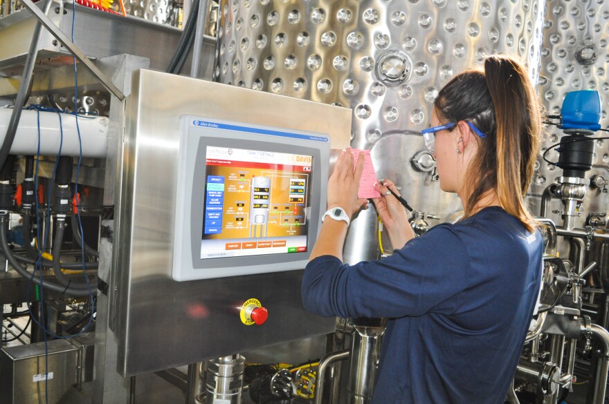 A student records information about a wine tank's sugar levels and juice temperatures on a computer screen inside UC Davis' research winery. In the future, students will also be able to monitor information about Clean in Place processes (which save water) using these screens.