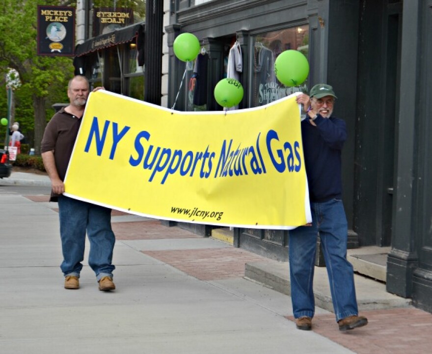 two men carry yellow banner with green letter saying 'NY Support Natural Gas'