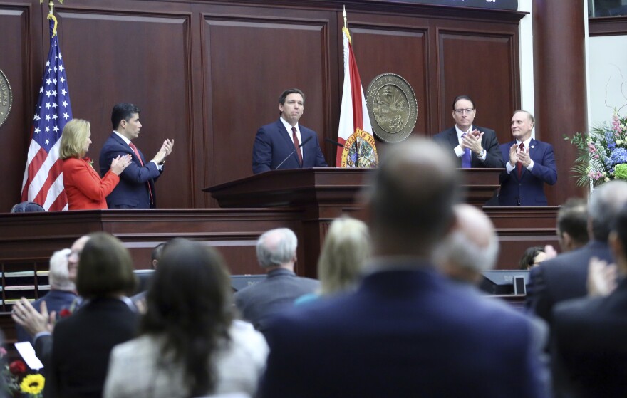 Man stands up on a podium. People around him are clapping.