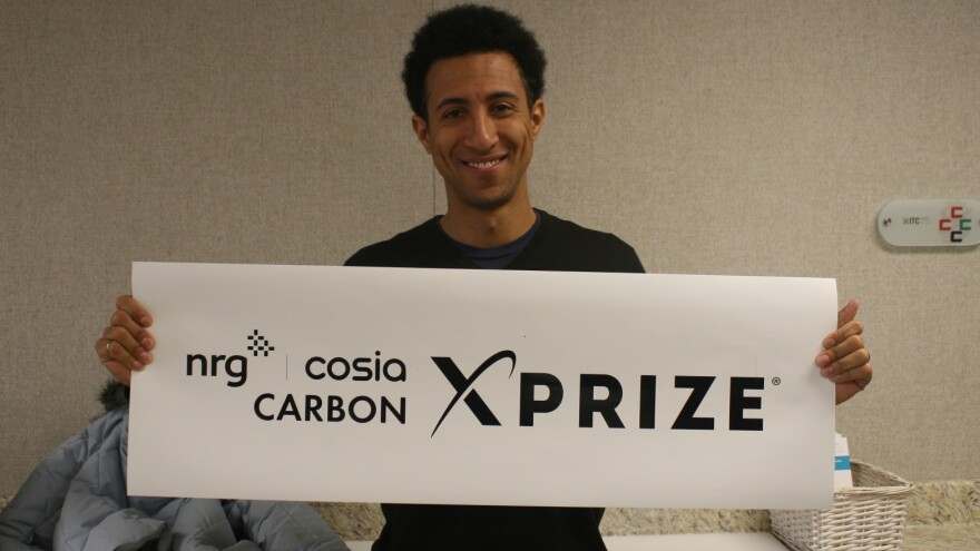 Marcius Extavour, executive director of NRG COSIA Carbon XPRIZE holding up a banner inside the Integrated Test Center in Gillette, Wyo.