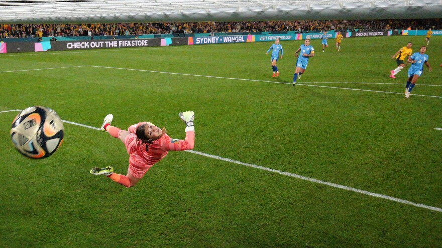 English goalie Mary Earps dives in vain as Australia's Sam Kerr, far right, blasts a goal past her in their Women's World Cup semifinal, in a photo taken from a remote camera inside the goal.