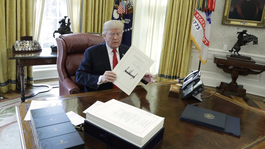 President Donald Trump displays the $1.5 trillion tax overhaul package he had just signed on Dec. 22, 2017 in the Oval Office of the White House.