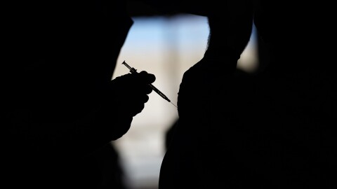 A silhouette of someone receiving a vaccine. 