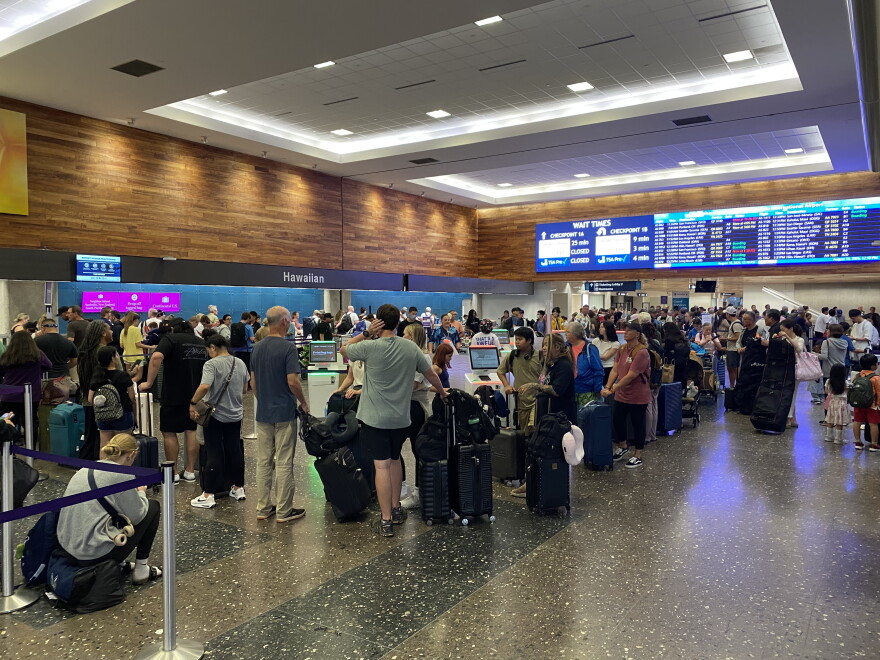Crowds of people at the Honolulu airport on Sunday, Aug. 16, are seen trying to check in and looking at the display monitor to see if their flights had been delayed or canceled.