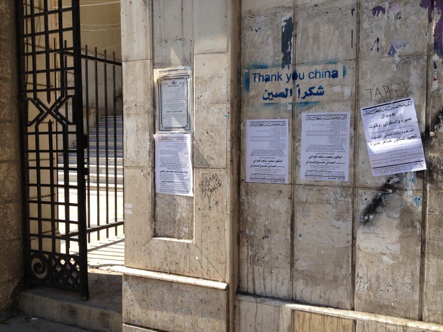 Death notices hang on a wall alongside pro-regime graffiti in central Damascus.