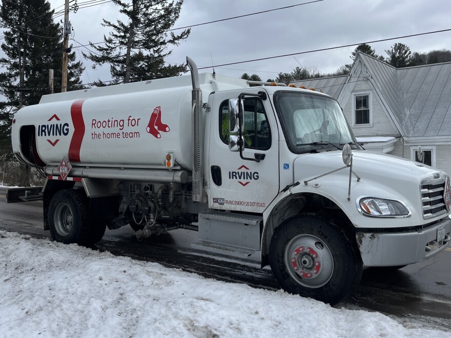A white fuel truck with a sign that reads IRVING on it in red sits parked on a snowy street.