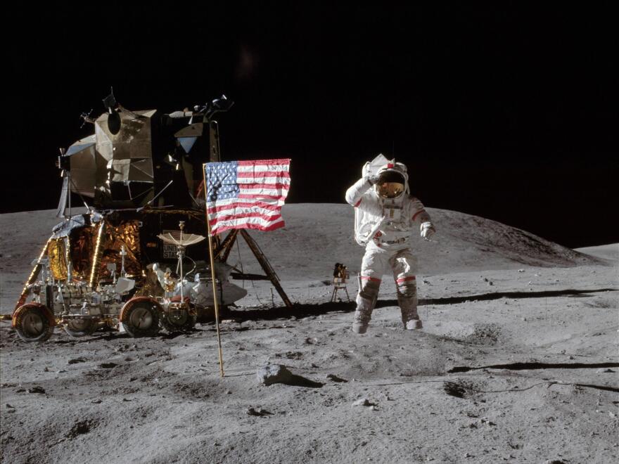 On the moon in 1972, Apollo 16 astronaut John Young jumps off of the lunar surface to salute the U.S. flag.