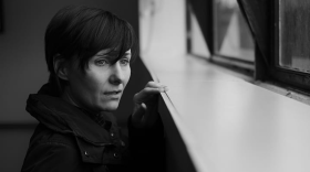 black and white image of a grieving woman looking out a window 