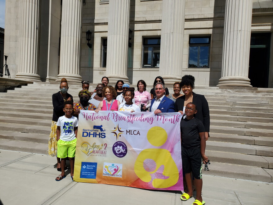  Advocates for breastfeeding hold up a National Breastfeeding Awareness Month flag on the steps of Springfield City Hall in Springfield, Massachusetts.  
