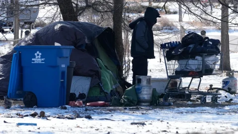 A homeless person checks a cart in front of a tent during a cold day in Chicago, Thursday, Jan. 22, 2026.