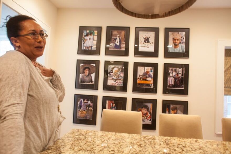 Adrienne Davis in front of her photographs by her father Wayne Davis from Zanzibar, Greece, China, Hong Kong, Egypt, Kenya, and Guatemala.