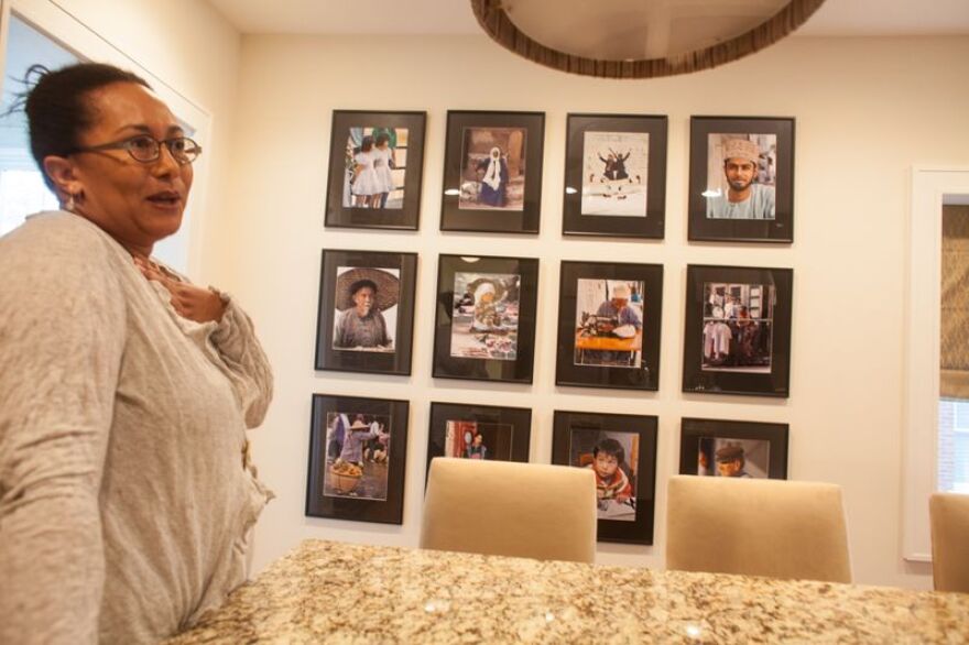 Adrienne Davis in front of her photographs by her father Wayne Davis from Zanzibar, Greece, China, Hong Kong, Egypt, Kenya, and Guatemala. 