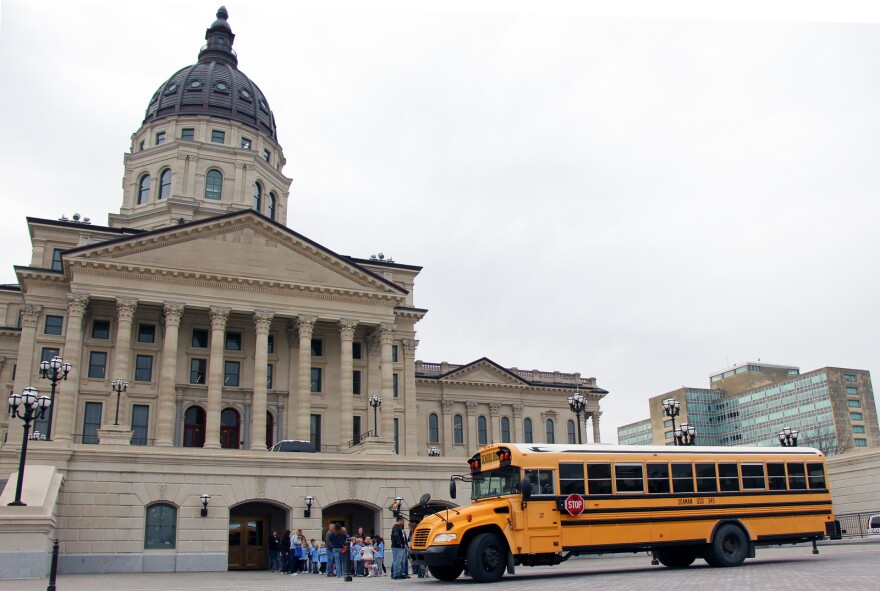 Students leave a school bus parked outside of the Kansas State Capitol. 