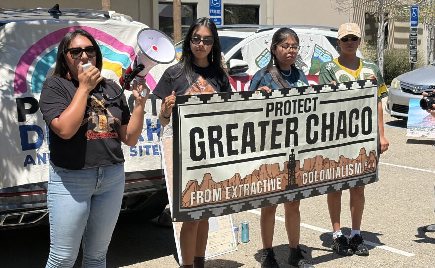 Executive Director for the Pueblo Action Alliance Julia Bernal (left) speaks through a megaphone alongside Alicia Gallegos, Leeona Goatson and Kira Padilla on July 29, 2026, outside the Bureau of Land Management’s Santa Fe office to protest.