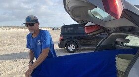 Former plastics engineer Neil McQueen pulls his board out to surf the waves off Mustang Island in Texas. Neil now fights against plastic pollution plaguing Texas' beaches and coastal waters.