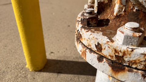 Picture of a white-ish colored gas meter with some corrosion. 