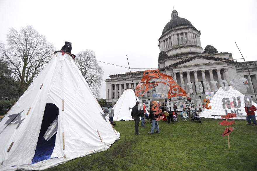 Environmental activists gather around structures erected on a grassy area in front of the Legislative building at the Capitol in Olympia, Wash., Monday, Jan. 8, 2018, the first day of the 2018 legislative session.