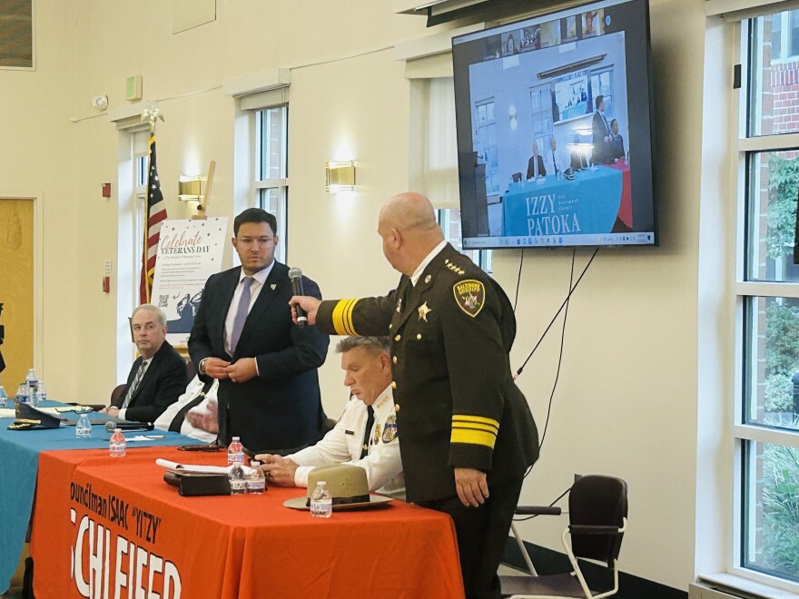 Baltimore City Sheriff Sam Cogen hands a microphone to Councilman Schleifer. Photo by Wambui Kamau/WYPR.