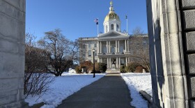 A view of the New Hampshire State House with snow on the ground.