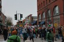 Protesters march across a street in downtown Burlington. Some hold signs that say things like "ICE Out" and "ICE Out of VT"