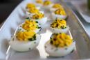 A narrow white plate with two rows of deviled eggs on it.