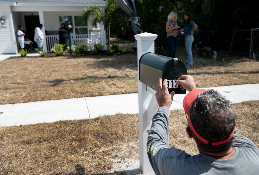 Dennis Cowan, a project manager for Builders Care, puts address numbers on Myrtle Dillard's new mailbox on Tuesday, May 7, 2024, in Fort Myers. Builders Care and Stevens Construction built Dillard and her family a new home after seeing that their nearly 100-year-old home was in disrepair.