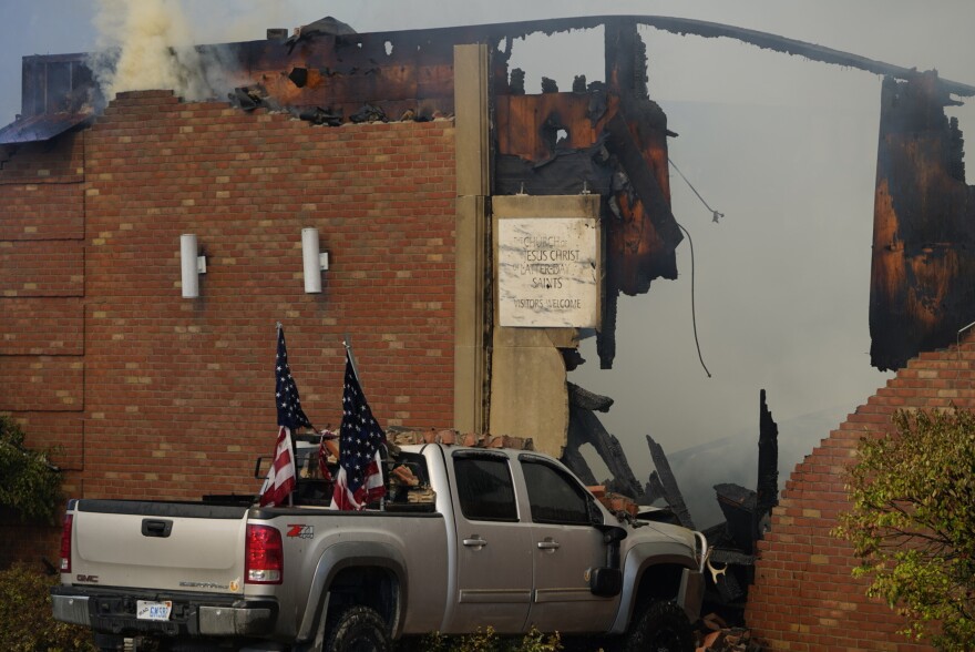 A vehicle that was rammed into the building is surrounded by smoke at the Church of Jesus Christ of Latter-day Saints in Grand Blanc, Mich., Sunday, Sept. 28, 2025. 