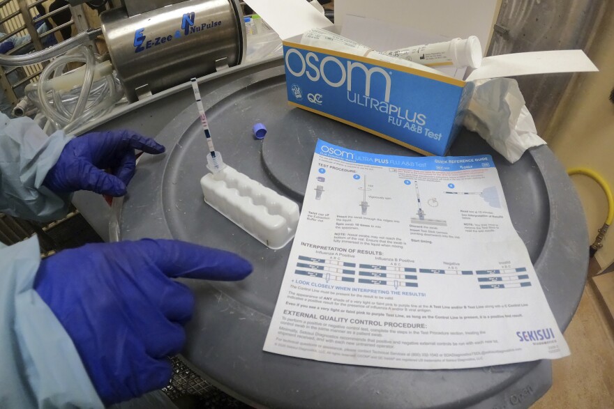 In this image provided by the U.S. Department of Agriculture via the AP, a researcher performs a rapid antigen test on milk from a dairy cow inoculated against bird flu in a containment building at the National Animal Disease Center research facility in Ames, Iowa, on Monday, July 29, 2024.