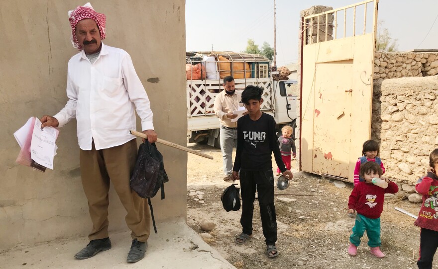 Hassan Murad returns to his damaged home in the village of Wardiya, in Sinjar province, with his wife and five young children. He holds the official documents he needed to return. A teenager from the village helps carry things in.