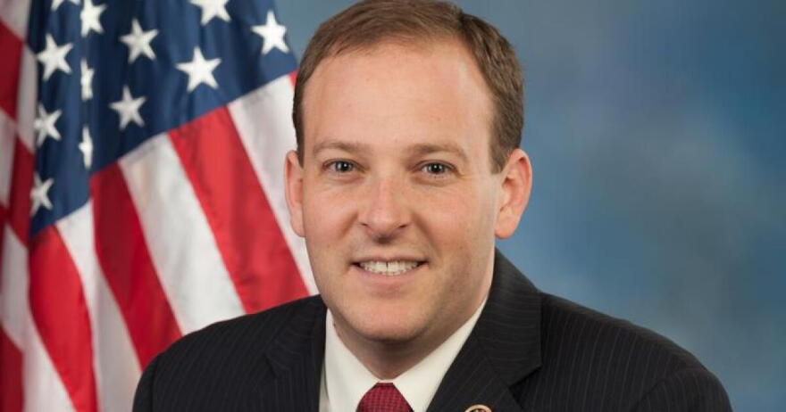 A headshot of Lee Zeldin in front of an American flag