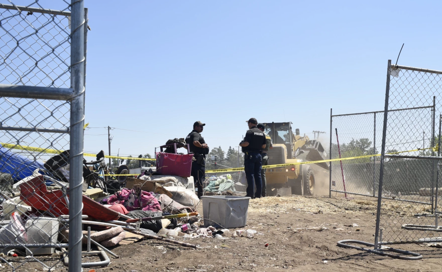 Law enforcement officers watch as heavy machinery clears the encampment on Eaton and Cohasset roads in Chico, Calif., on Aug. 5, 2024.