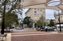 A brick- paved pedestrian square in downtown Athens with beige shade sails hovering above.