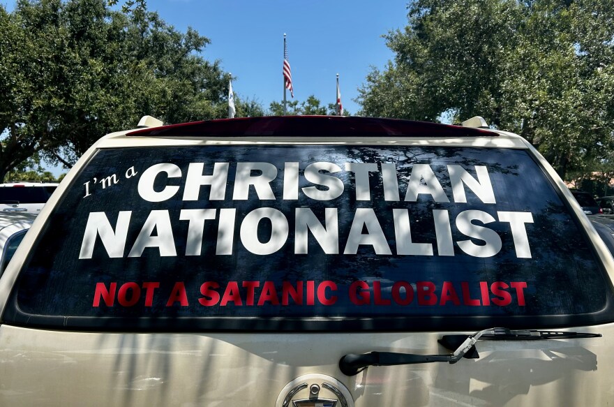 A car in a parking lot showing the rear window with the words I'm a CHRISTIAN NATIONALIST not a satanic globalist
