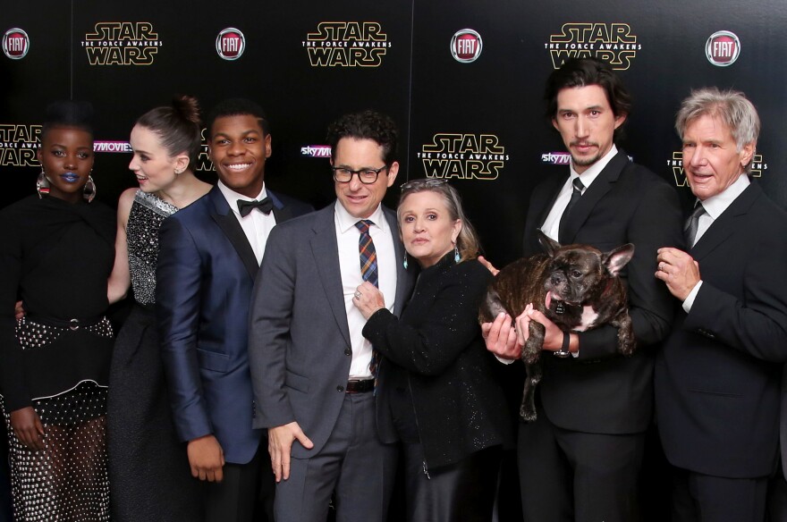 (From left) Lupita Nyong'o, Daisy Ridley, John Boyega, J.J. Abrams, Carrie Fisher, Adam Driver (holding Fisher's dog, Gary) and Harrison Ford pose for photographers upon arrival at the European premiere of the film <em>Star Wars: The Force Awakens</em> in London in December 2015.