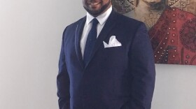 James Austin poses for a photo in a blue suit with a blue tie. 