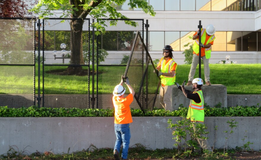 Workers take down parts of a fence. 