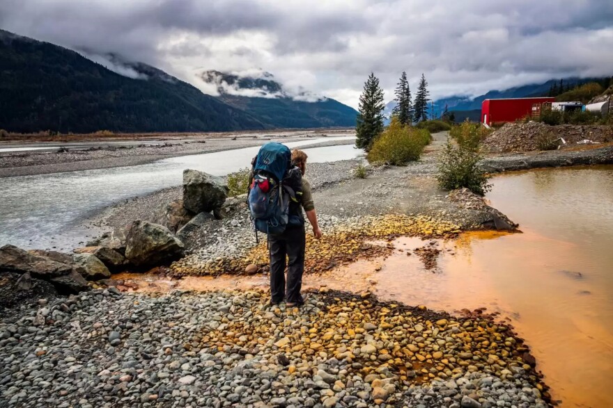 A man stands in front of acid mine drainage from British Columbia’s Tulsequah Chief Mine, which has been leaching acid mine drainage into the transboundary Taku River since it was abandoned in 1957.