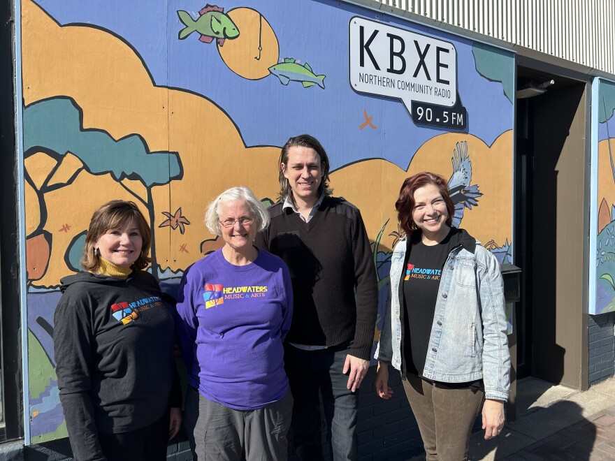 Four people standing in front of mural or nature with the sun shining.