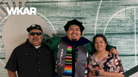  En la imagen se puede observar a Jose Guadalupe Hernandez con su vestimenta de graduacion en frente de un rotulo de la Michigan State University. El se encuentra abrazando a sus padres. En el lado inferior de la imagen esta el logo de ¿Qué Onda Michigan? sobre un fondo blanco. En la parte derecha las siguientes palabras estan escritas: "La historia de los estudiantes latinos que se graduaran de la Michigan State University." En el lado superior de la imagen se encuentra las palabras "WKAR" en color blanco.  y "Episodio 90".