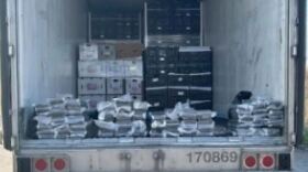A photo of the interior of a refrigerated box truck containing packages of cocaine stacked at the edge of the opening