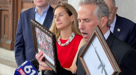 Jeremy Stein of Connecticut Against Gun Violence holds pictures of the Sandy Hook victims and the type of rifle used to kill them at a press conference Tuesday.