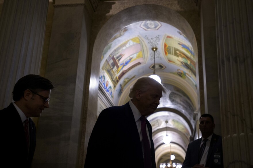 Silhouetted by lights in the hallway, President Donald Trump, right, is joined by Speaker of the House Mike Johnson, R-La., as he departs the Capitol following a meeting with the House Republican Conference, Tuesday, May 20, 2025, in Washington. (AP Photo/Rod Lamkey, Jr.)