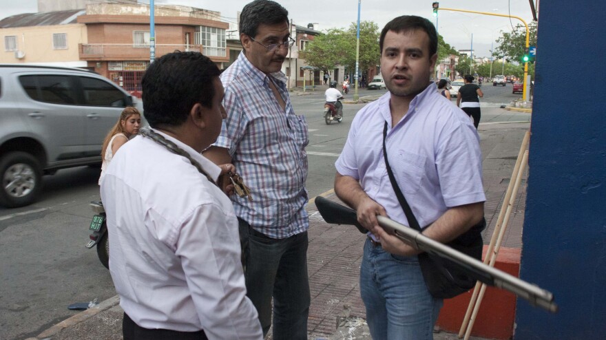 An armed shopkeeper stands outside his shop after it was looted in San Miguel de Tucuman, Argentina, on Monday. The country's government dispatched federal police to trouble spots as looting spread early this week.