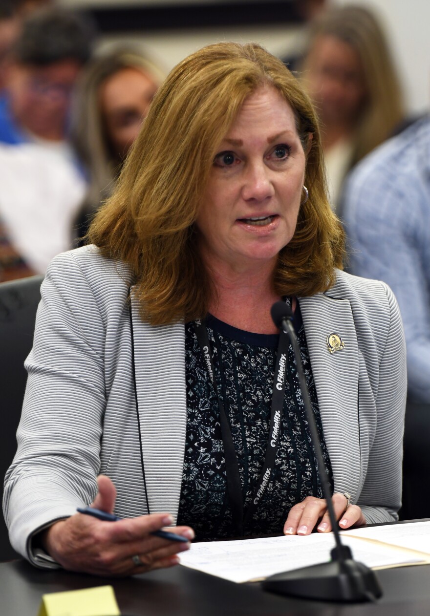  Kim Moser sits at table in legislative committee room