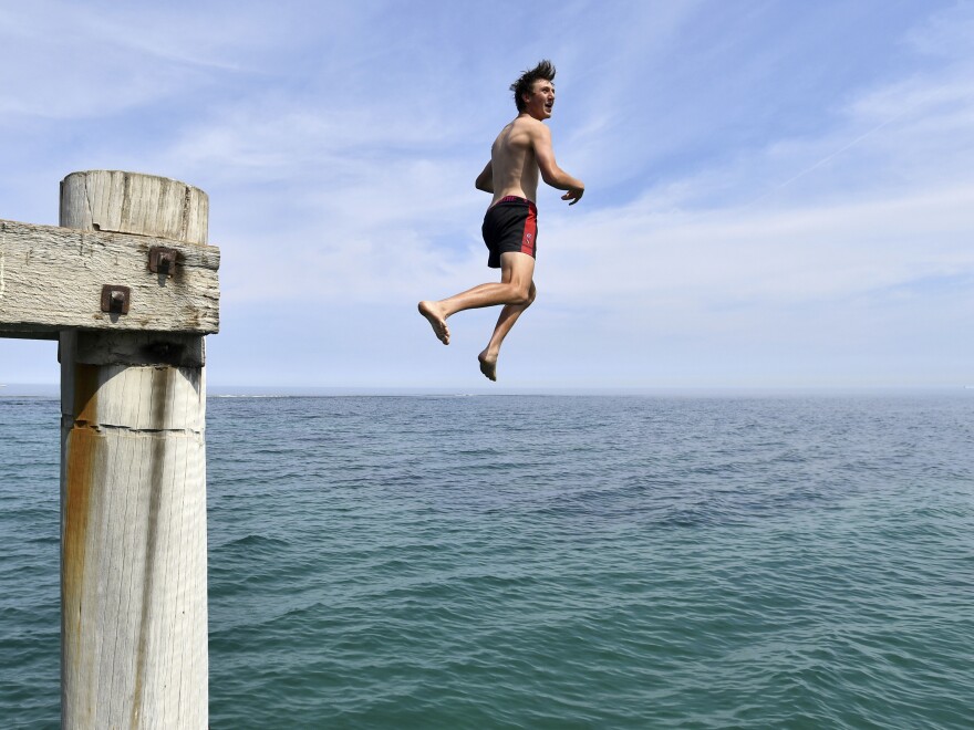 A swimmer jumps from a jetty in an effort to cool off in Adelaide, Australia, as the country experiences record temperatures.