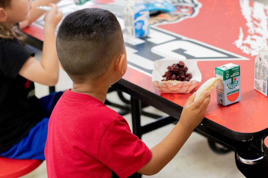 A pre-kindergarten student eats a peanut butter and jelly sandwich during "third meal" at Whitebead Public Schools.