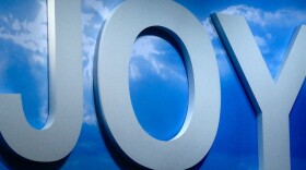 the word "joy" in white letters against a bright blue sky